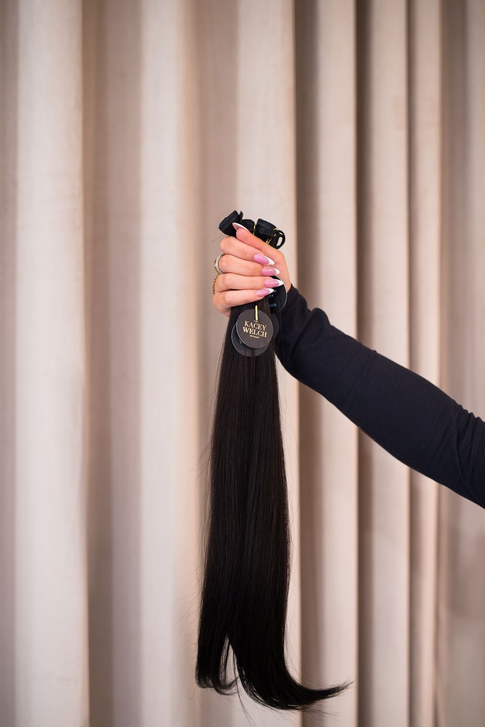 A stylist holding up a long dark weft to match length and color