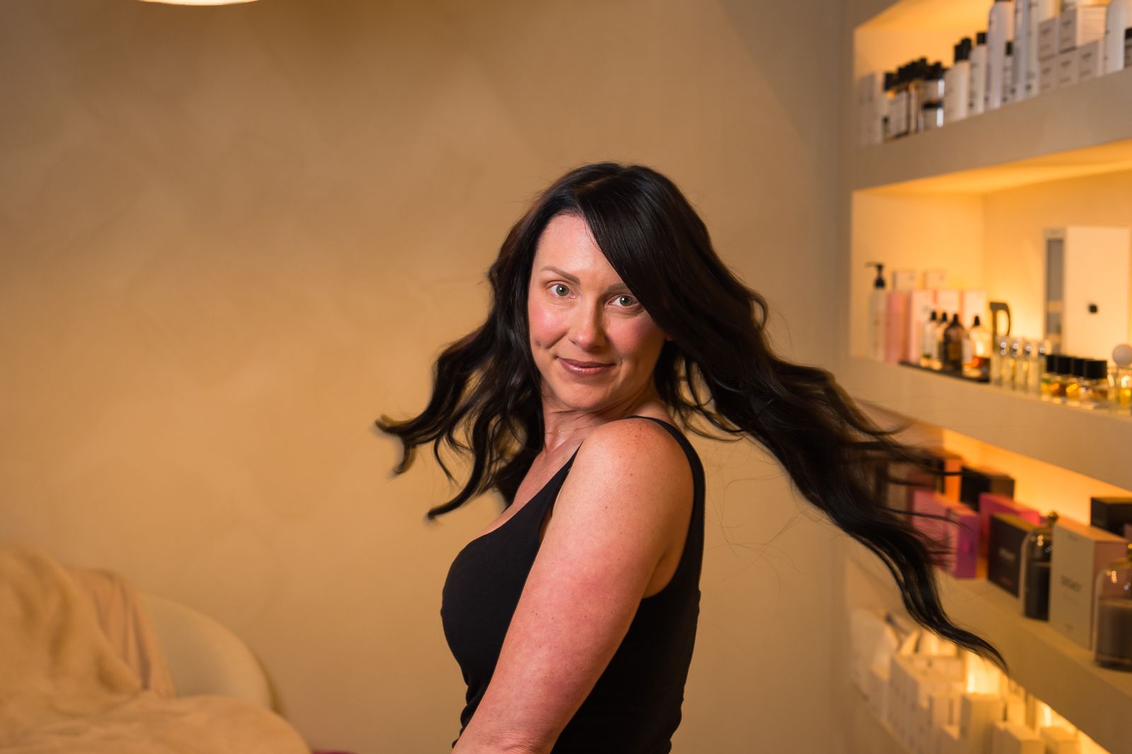 A Studio Beige client flipping long, glossy dark extensions inside the atelier