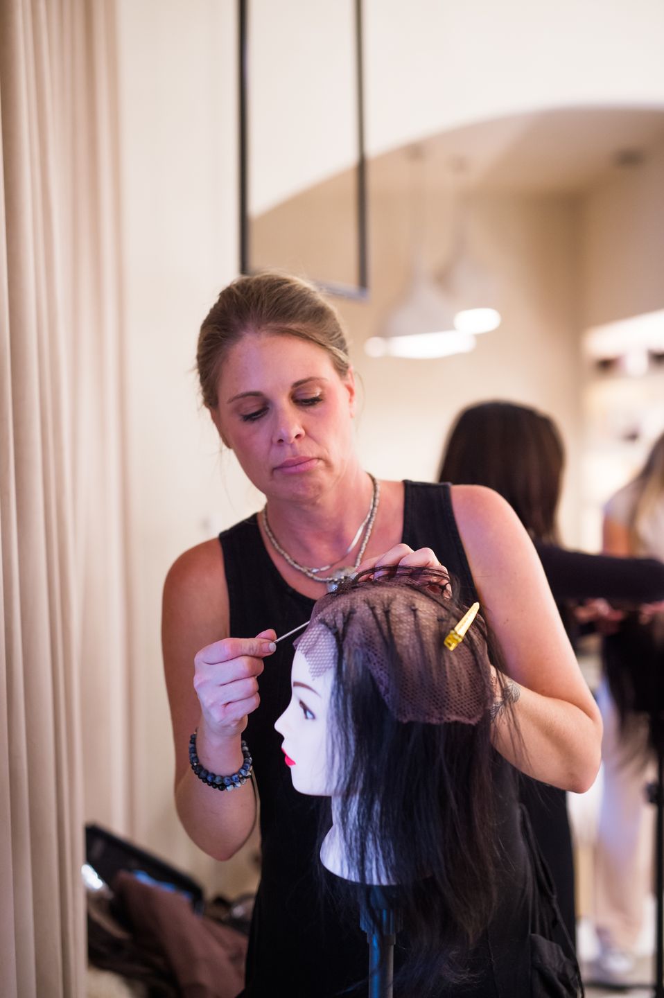 Stylist adjusting a hair unit on a training head at Studio Beige